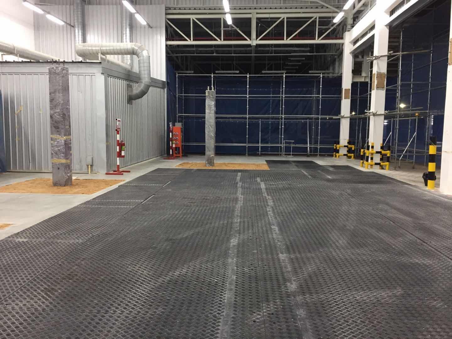 Construction site using temporary roadway panel and ground protection mat for heavy machinery